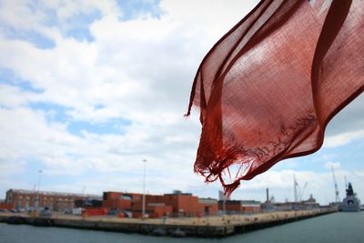 Close-up of torn flag hanging against sky