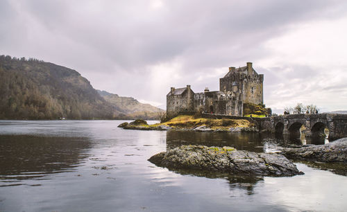 River by eilean donan castle against cloudy sky