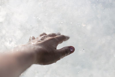 Cropped image of wet hand against pool