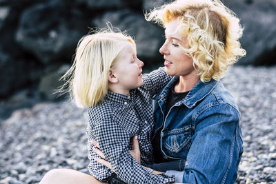 Happy woman and son with blond hair sitting at beach