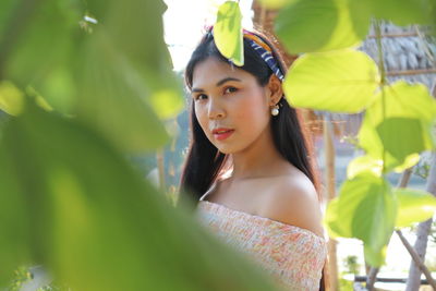 Portrait of young woman looking away while standing on leaves