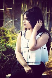 Young woman looking away while sitting outdoors