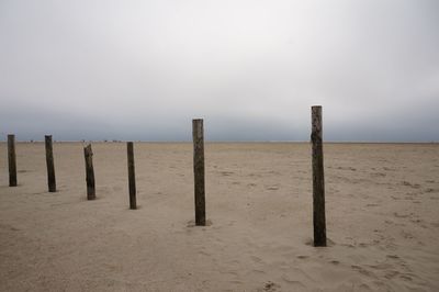 Wooden posts on beach against sky