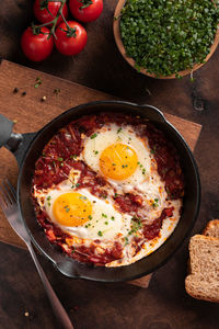 Israel traditional food shakshouka with micro greens in a cast-iron pan close up