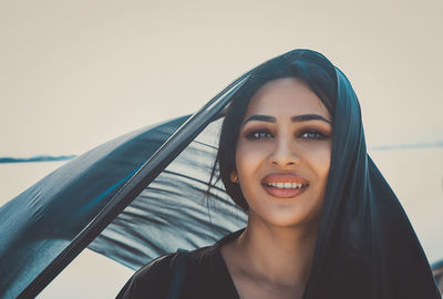 Portrait of smiling woman wearing headscarf against clear sky