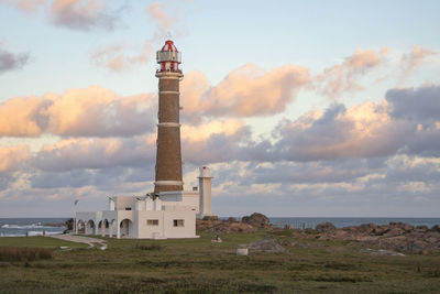 Lighthouse amidst sea and buildings against sky