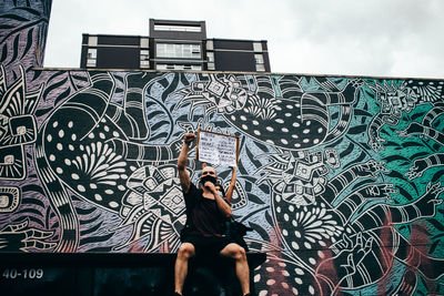 Full length portrait of woman standing against graffiti