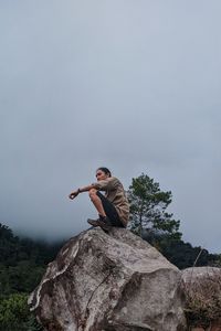 Man standing on rock against sky