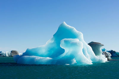 Ice floating on water against clear blue sky