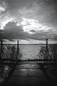 Pier on sea against cloudy sky