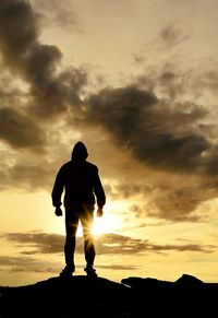 Silhouette man standing on rock against sky during sunrise