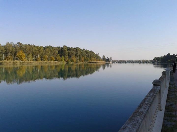 water, clear sky, reflection, lake, tranquility, tranquil scene, copy space, blue, tree, scenics, beauty in nature, nature, river, standing water, calm, built structure, idyllic, no people, outdoors, waterfront