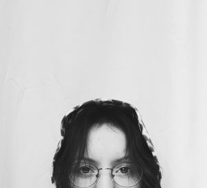 Portrait of young woman wearing eyeglasses against white background