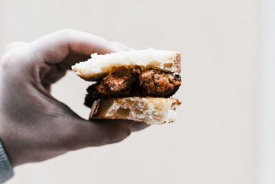 Close-up of hand holding bread against white background