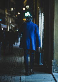 Rear view of man walking on street at night