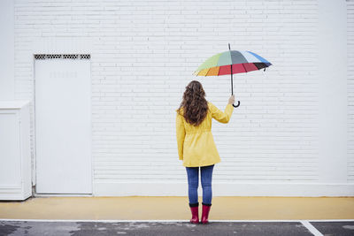 Woman holding multi colored umbrella on footpath