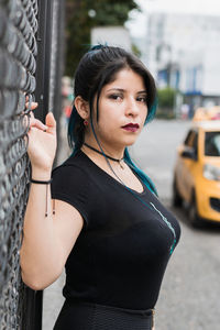 Beautiful latin girl on the street leaning on a wire mesh in a close-up