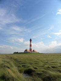 Lighthouse on field against sky