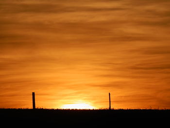 Silhouette of field against sky at sunset