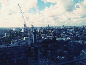 Aerial view of cityscape against cloudy sky