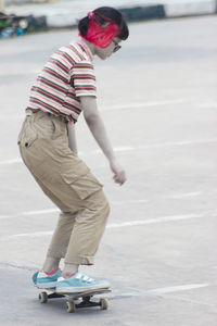 Low section of boy skateboarding on road