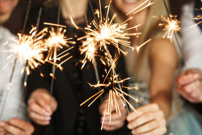 Out of focused image of party people with burning sparklers celebrating holiday or event