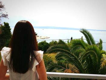 Rear view of woman standing at beach against clear sky