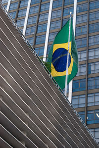 Low angle view of flag in modern building against sky