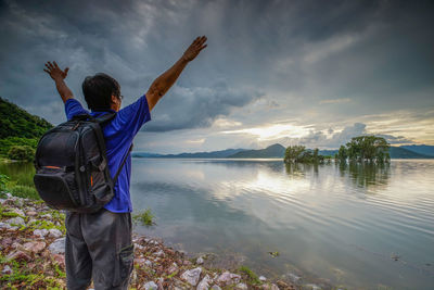 Rear view of man standing in water against sky