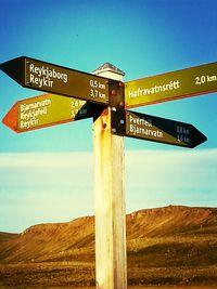 Low angle view of road sign against blue sky