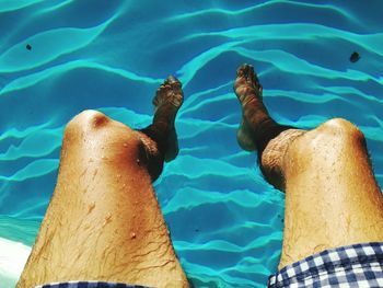 Low section of man swimming in pool