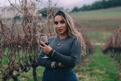 Beautiful young woman using phone while standing on field