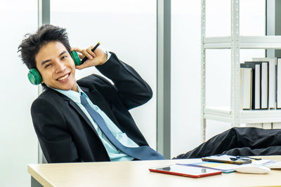 Young woman using phone while sitting on table