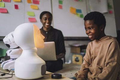 Happy student communicating with illuminated social robot at innovation lab