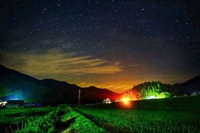 Scenic view of illuminated field against sky at night