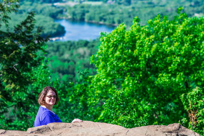 Portrait of smiling young woman against trees