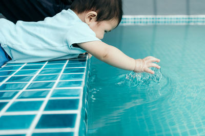 Cute baby girl playing with water in swimming pool