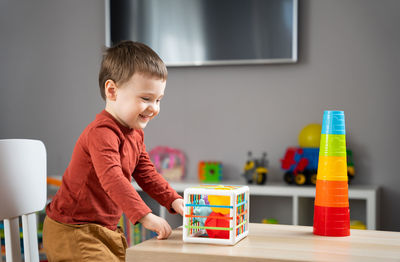 A cute little toddler boy of two years old plays with multi-colored balls 