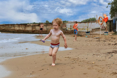 Full length of shirtless boy running on beach