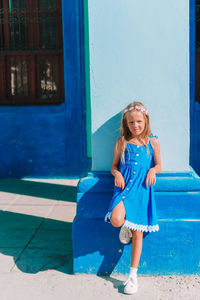 Full length of smiling girl against blue wall