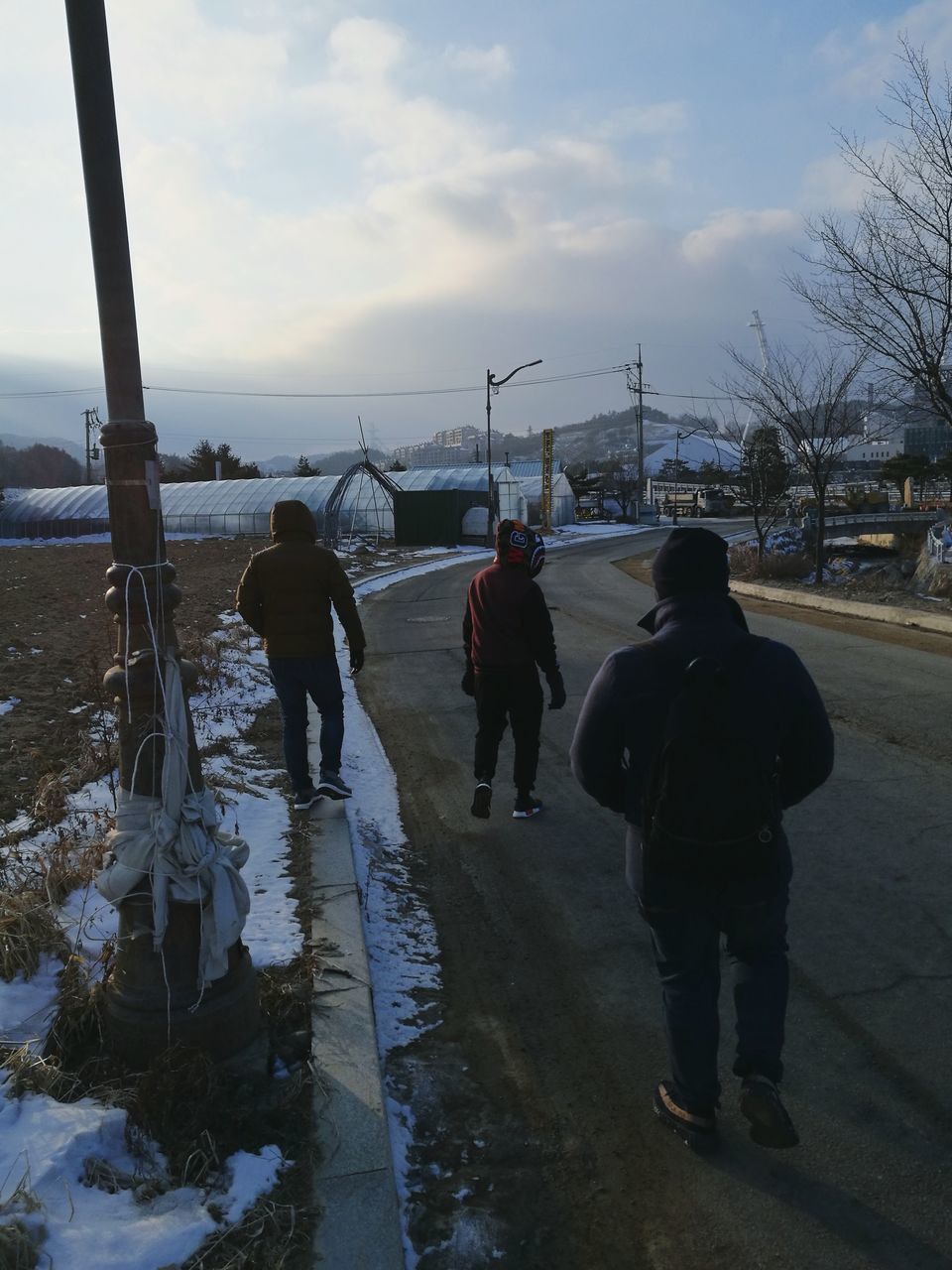 REAR VIEW OF PEOPLE STANDING ON SNOW COVERED SHORE