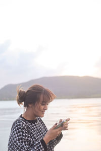 Woman using mobile phone against sea