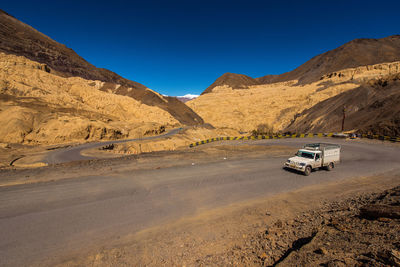 Semi-truck on road by mountains against sky