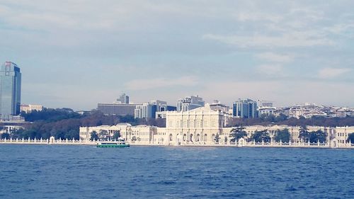 Sea and buildings in city against sky