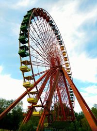 Low angle view of ferris wheel against cloudy sky