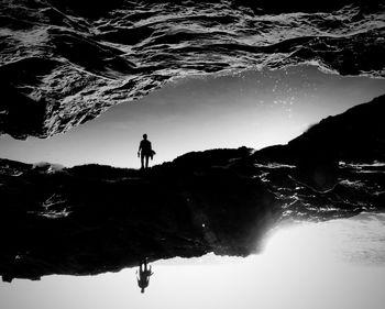Rear view of silhouette man on mountain against sky