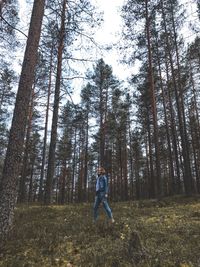 Man standing by trees in forest