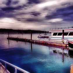 Boats in sea against cloudy sky