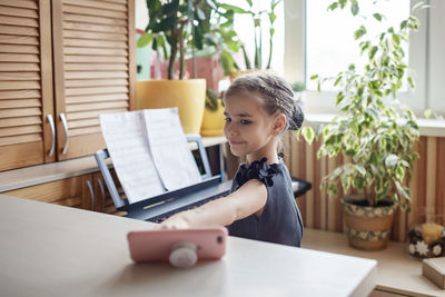 View of cute girl sitting by piano at home