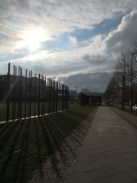 Footpath amidst trees against sky during sunset